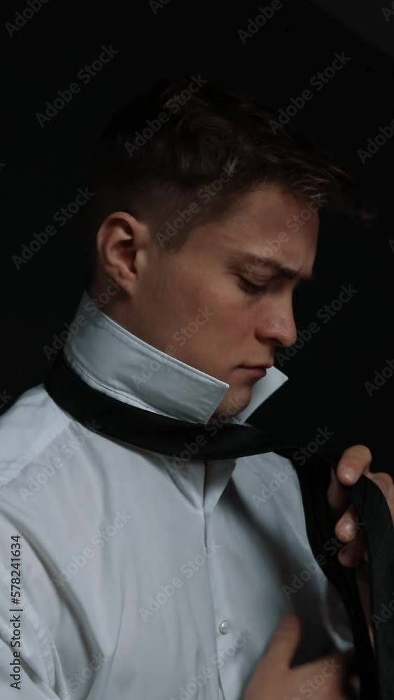 A serious man in a state putting on a black tie A serious man in a state putting on a black tie