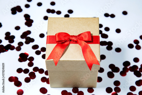 Gift box with red ribbon on white background with dark red spotes photo