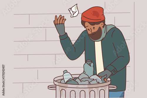 Homeless man digs through garbage to find food due to poverty and social inequality or unemployment