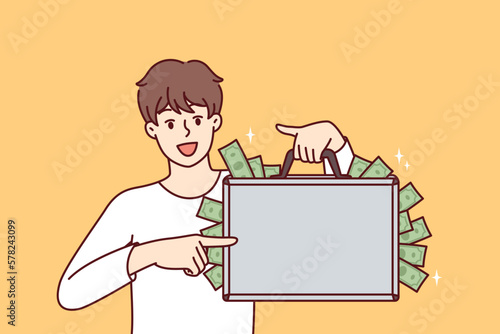 Happy man with suitcase full of money showing off big profits from own business or cash won at casino. Rich guy who made lot of money after selling real estate or received unexpected inheritance