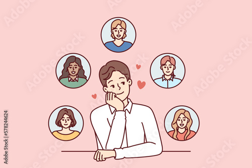 Young monogamous man thinks about girls while choosing which fan to invite on romantic date. Monogamous guy loves several women at same time and introduces them while sitting at table
