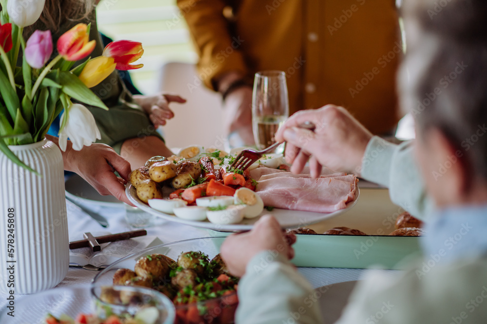 Close up of muligenerational family serving Easter dinner together. - obrazy, fototapety, plakaty 