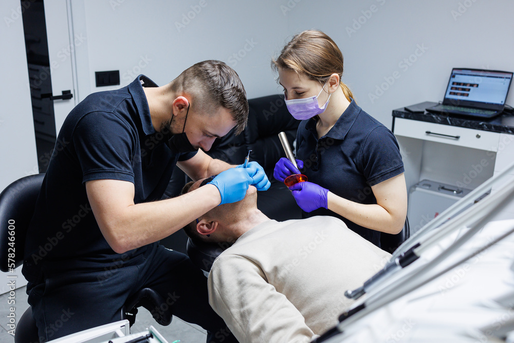 An orthodontist with an assistant treats teeth using dental instruments. Dental office. Orthodontic treatment of teeth An orthodontist with an assistant treats teeth using dental instruments. Dental office. Orthodontic treatment of teeth