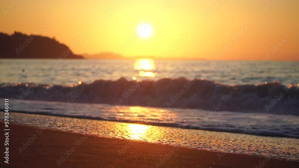 Golden sunset on the beach. Foamy waves rolling towards golden sand beach under low warm sun light. Slow motion. Nobody. Holiday recreation concept. Abstract nautical summer ocean sunset nature. Golden sunset on the beach. Foamy waves rolling towards golden sand beach under low warm sun light. Slow motion. Nobody. Holiday recreation concept. Abstract nautical summer ocean sunset nature.