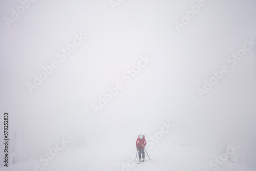A woman backcountry skier touring a whiteout ridge in Montana
