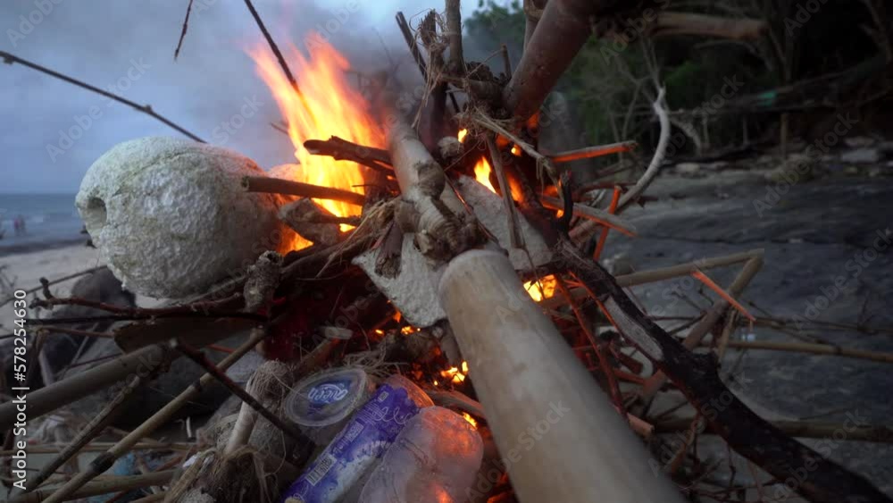 Fire on the beach with plastic parts and garbage. Blazing campfire on