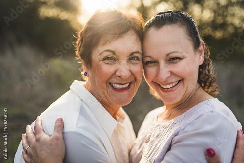 close up portrait of adult mother and daughter embracing and smiling photo