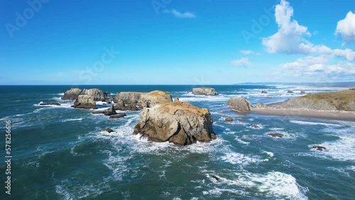 Beautiful 4K aerial drone shot hovering towards giant rock in Bandon, Oregon. Landscape view with poppy blue sky. photo