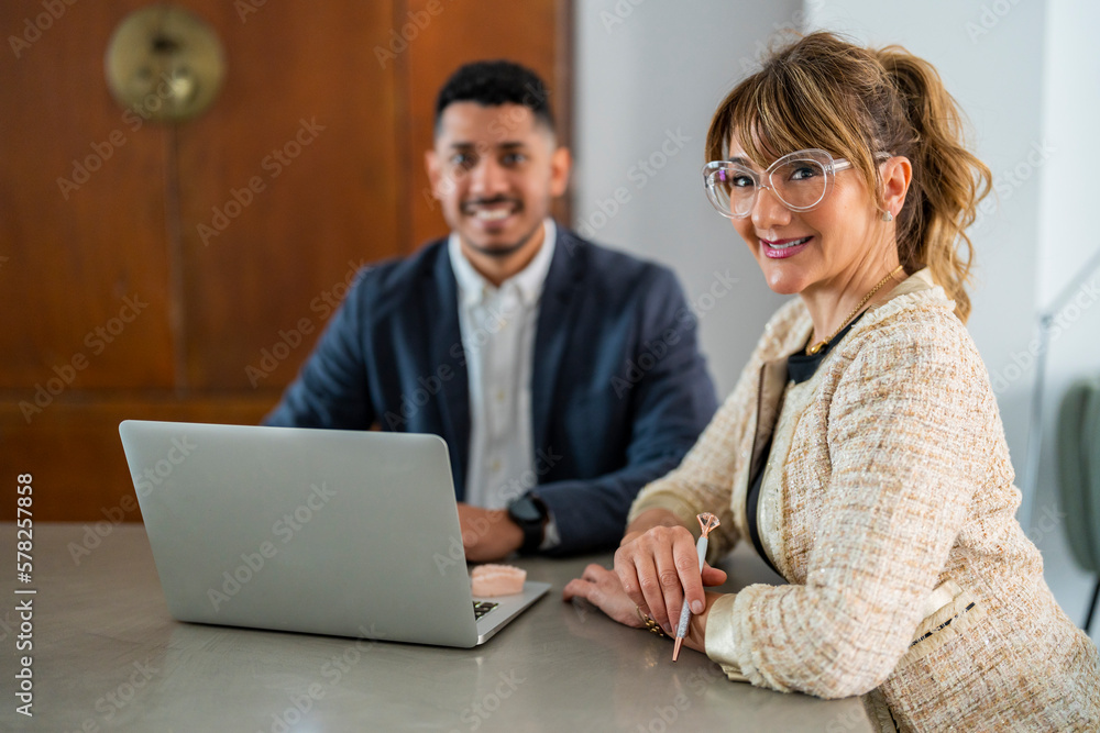 Smiling businesswoman sitting with colleague in office