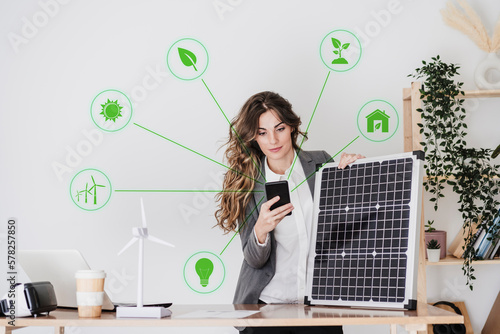 Young businesswoman with solar panel using smart phone