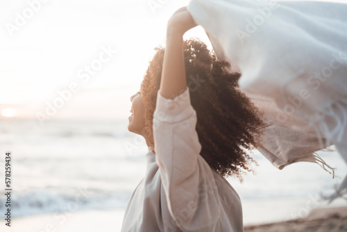 Happy young woman holding scarf at beach photo