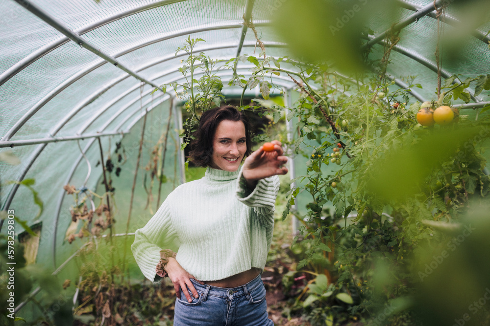 Smiling woman holding fruit standing in garden Smiling woman holding fruit standing in garden