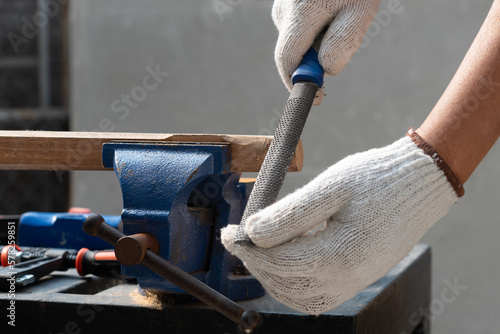 Male hobby retirement. Senior man is using rasp on wood  for assembling hammer handle. photo
