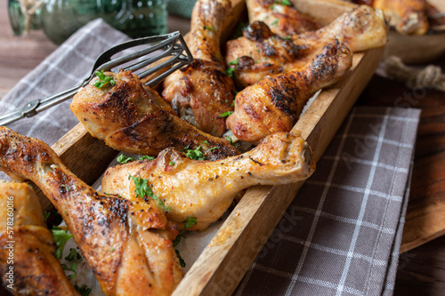 Roasted chicken drumsticks in a wooden bowl on rustic background.