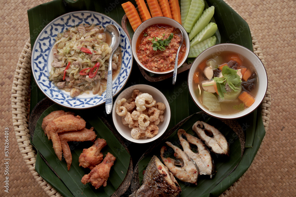 `Closeup Food scene of Local Thai Food Northern Style - Fish Chicken Pork  Fried , Soup , Stir Fried Vegetable and chili sauce  seen From Doing SaKad Pua Nan Thailand 