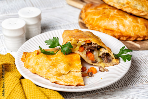 Fototapete Baked meat turnovers or pies, or empanadas, or cornish pasty with filling, beef, carrot, and potato, white plate