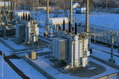Top view of a small electrical substation with rows of transformers. Electrical substation in the winter in the rays of the rising sun.