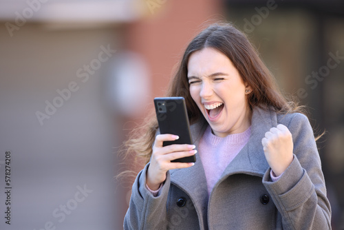 Excited woman celebrating good news holding phone