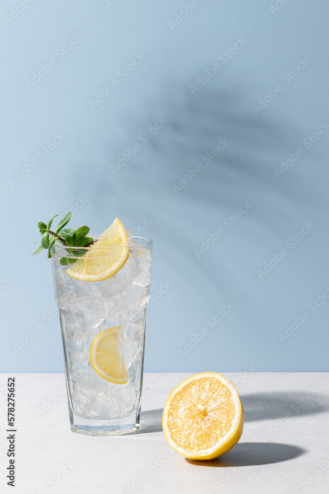 Refreshing drink with ice, lemon and mint. Cold lemonade on blue background - obrazy, fototapety, plakaty 