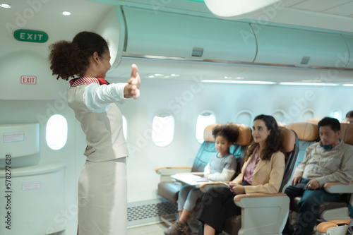 Flight attendants show how to use safety devices and recommend emergency exits.