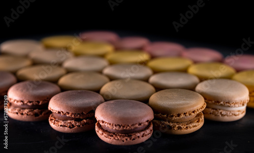 chocolate, coffee, vanilla, lemon and strawberry macaroons on black background