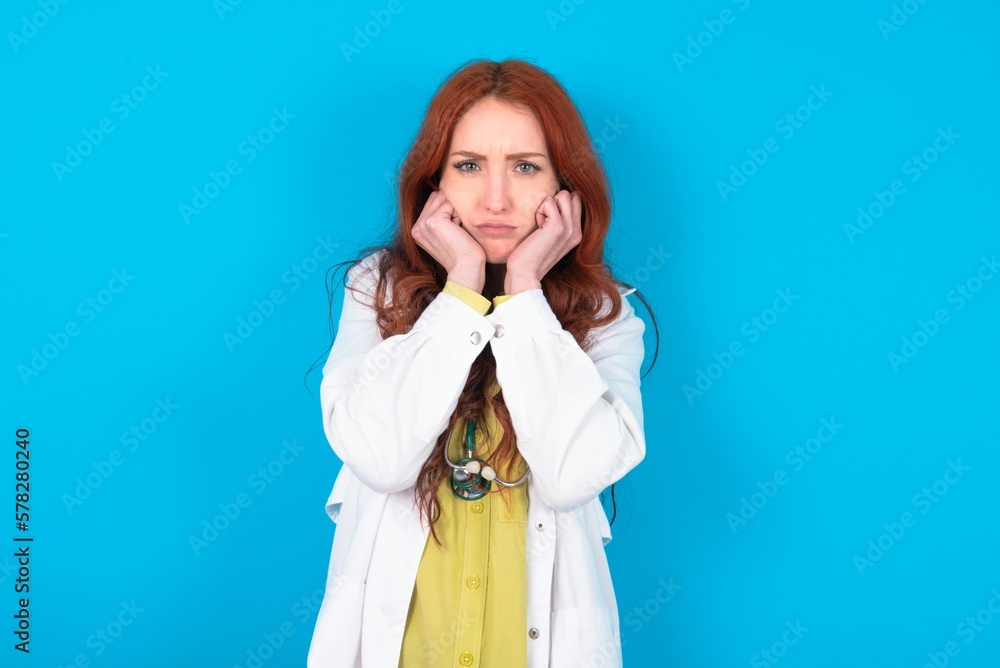 Portrait of sad young doctor woman wearing medical uniform over blue background hands face Portrait of sad young doctor woman wearing medical uniform over blue background hands face