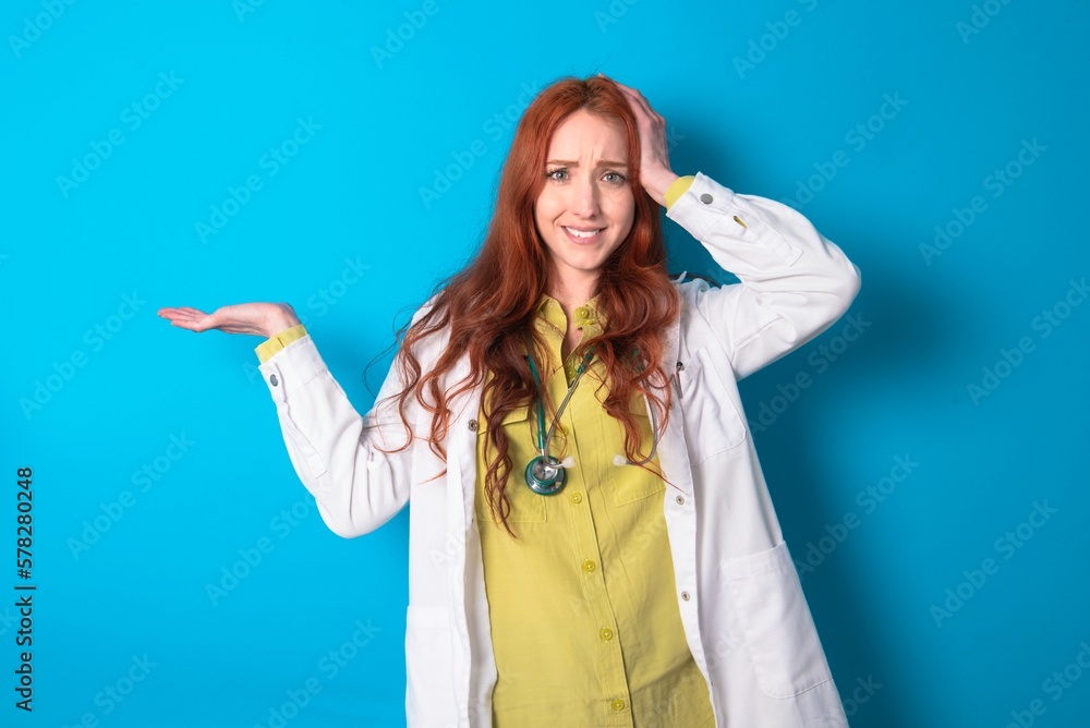 Shocked amazed surprised young doctor woman wearing medical uniform over blue background hold hand offering proposition Shocked amazed surprised young doctor woman wearing medical uniform over blue background hold hand offering proposition