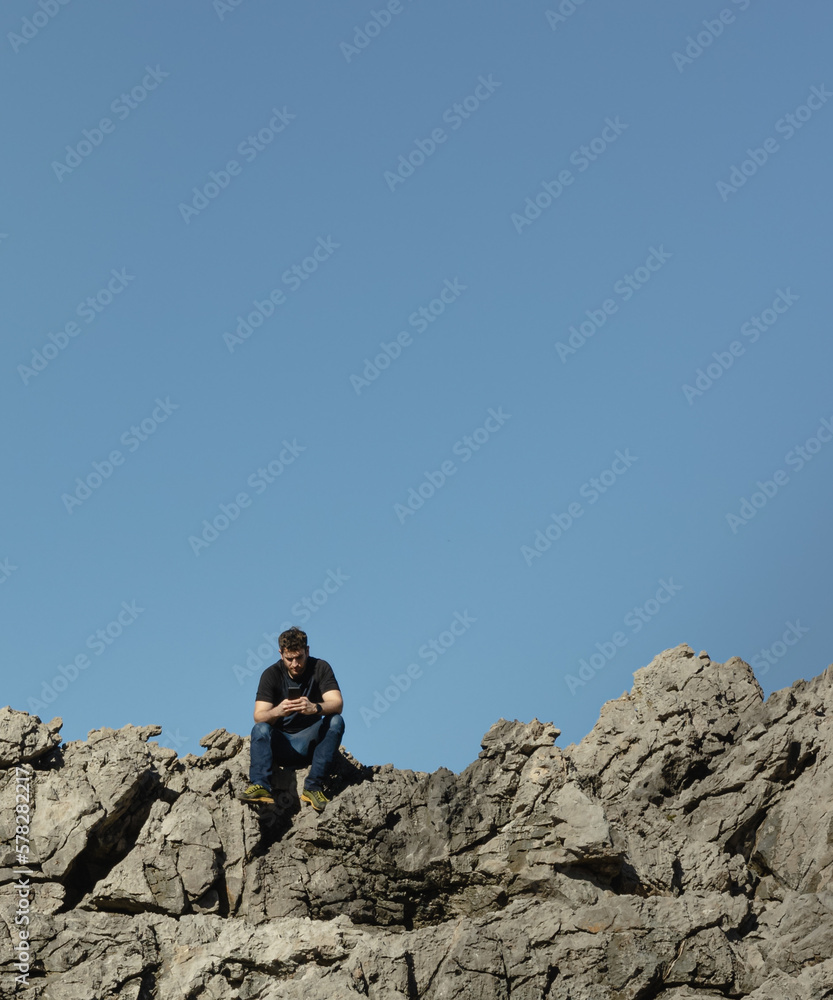 young boy looks at his cell phone on the mountain