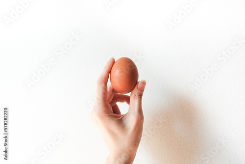 brown egg in asian woman hand on white background.
