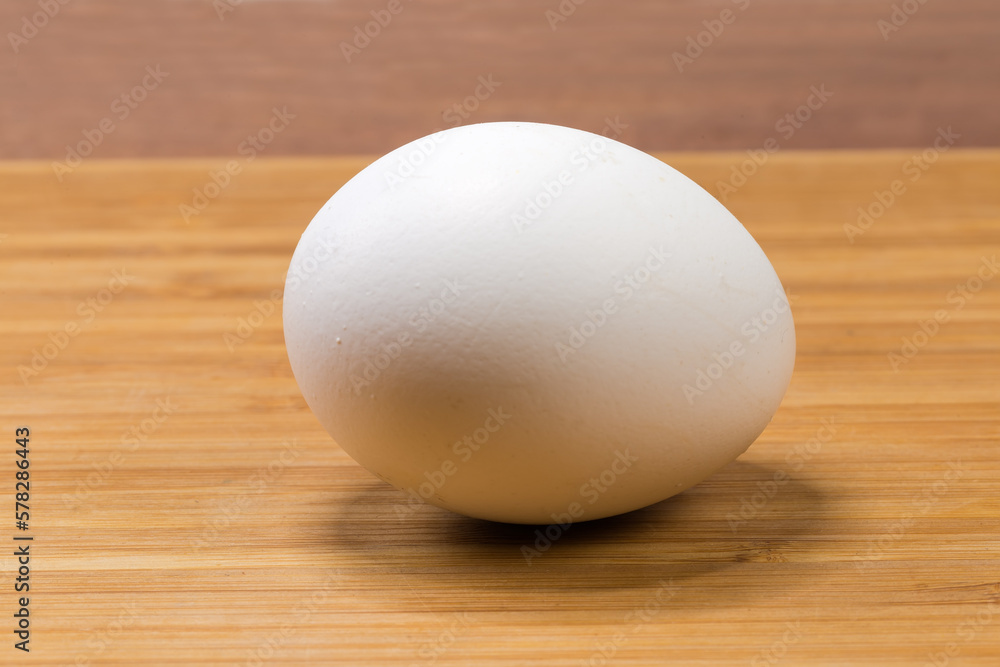 Whole white chicken egg on a wooden surface Whole white chicken egg on a wooden surface