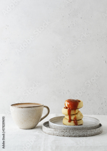 Breakfast minimal wabi sabi and kinfolk style table with cup of coffee, pancakes and caramel sauce © Denira