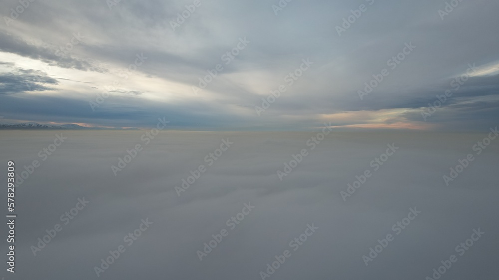 A heavenly ocean of clouds. Flying on a drone. The light yellow rays of the sun at sunset are reflected on the surface of the clouds. Double layer of clouds and heavy fog. Evening. Kazakhstan A heavenly ocean of clouds. Flying on a drone. The light yellow rays of the sun at sunset are reflected on the surface of the clouds. Double layer of clouds and heavy fog. Evening. Kazakhstan