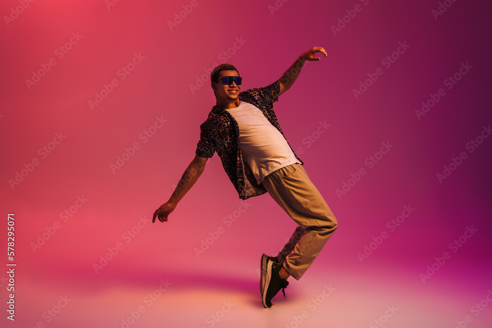 Joyful african man dancing isolated over pink neon background