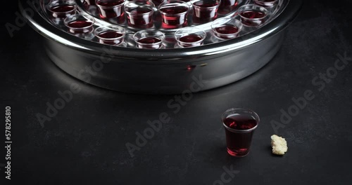Communion glass cups on tray filled with wine the symbol of Jesus Christ blood on black background. Easter Passover and Lord Supper concept. Dolly shot 4k