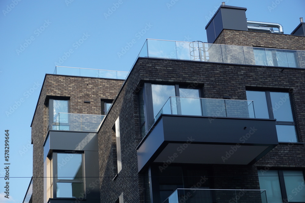 Modern residential building with balconies and dark brick facade. Real estate and housing issues concept.