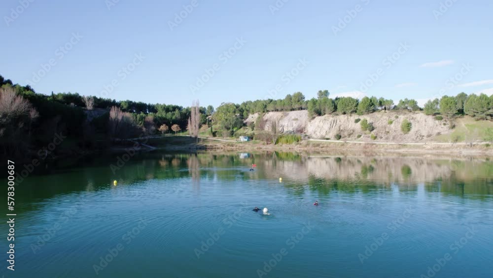 Slow aerial dolly above 3 divers out training Lac du Crès with safety buoys Slow aerial dolly above 3 divers out training Lac du Crès with safety buoys