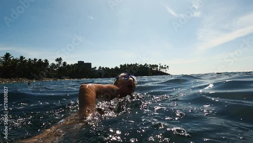Athletic young woman swimming freestyle at open water. Triathlon sea swimmer