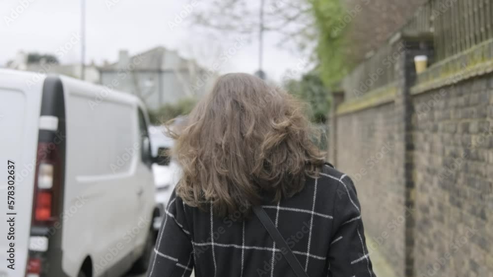 Backside view of businesswoman with long brown hair walking at busy street while wind blowing her hair in central London. Slow motion 60fps 4K. Backside view of businesswoman with long brown hair walking at busy street while wind blowing her hair in central London. Slow motion 60fps 4K.