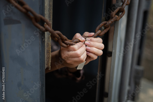 woman's hand trapped in an illegally smuggled container locked with chain and key. Efforts to escape from the confinement were tortured : Human Trafficking and Illegal Immigration. © lerm90