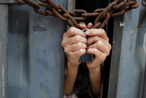 woman trapped in an illegal cargo container locked with chains and keys. Has the idea of trying to escape and seeking freedom from the outside : Concept of human trafficking
