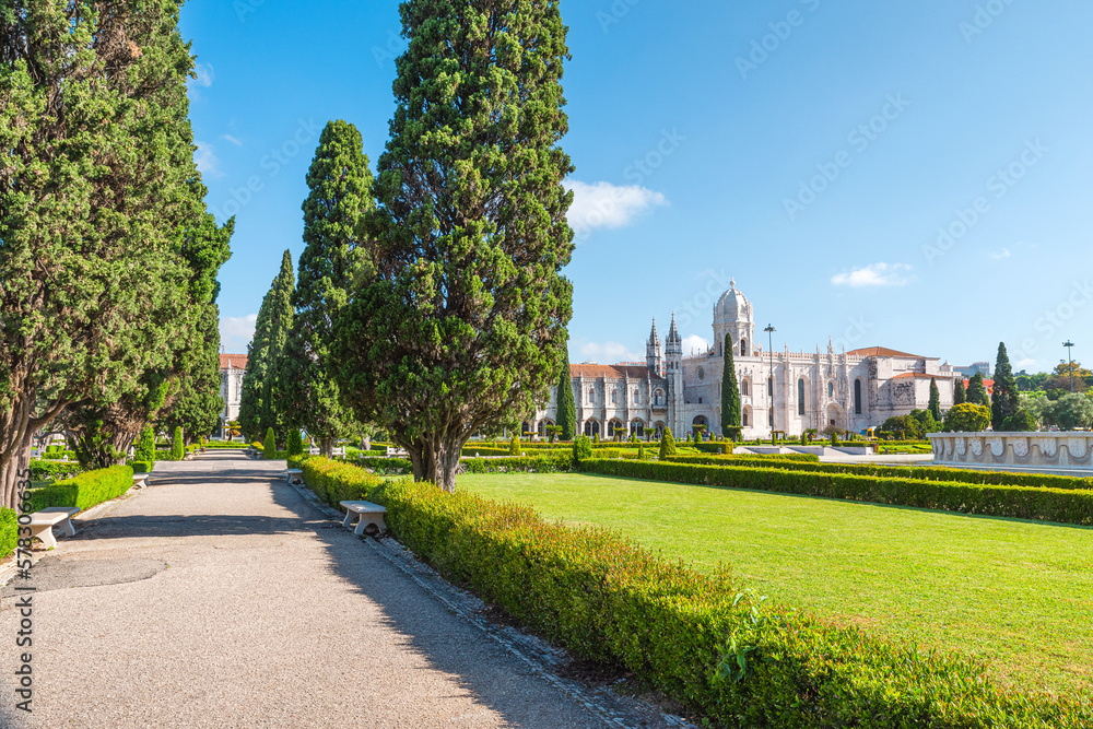 Gothic abbey in Belem district, Lisbon with alley and park in sunny day. Lisboa, Jeronimos Monastery or Hieronymites