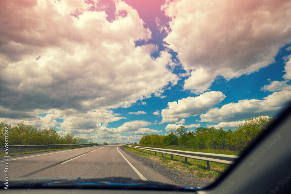 Highway with cloudy sky in summer. View of the road through the windscreen