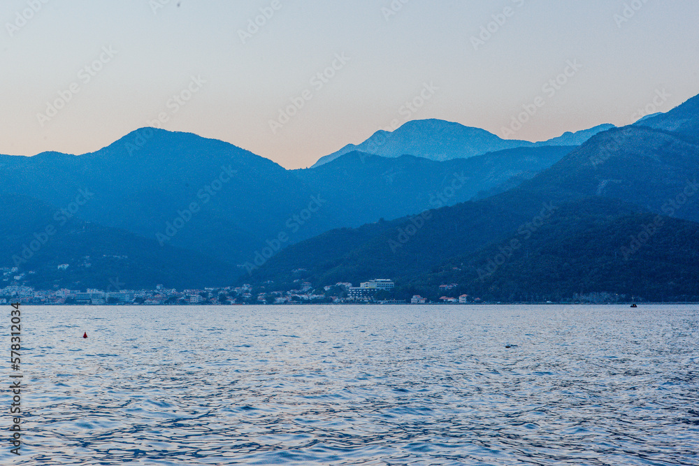 Seascape with blue silhouettes of the mountains after sunset for publication, design, poster, calendar, post, screensaver, wallpaper, postcard, banner, cover, website. High quality photo