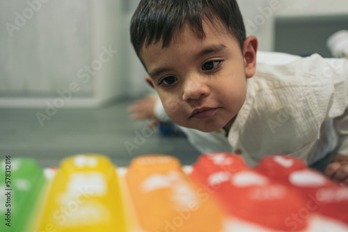 Foto Close-up floor level image of a young autistic child lying down looking closely at his musical key toy car