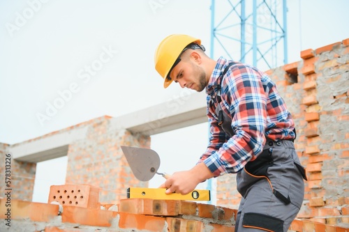 Obraz na płótnie construction mason worker bricklayer installing red brick with trowel putty knife outdoors