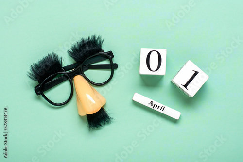 funny face - fake eyeglasses, nose and mustache, calendar with date 01 April on green background Happy fools day concept 1st April party Holiday greetind card