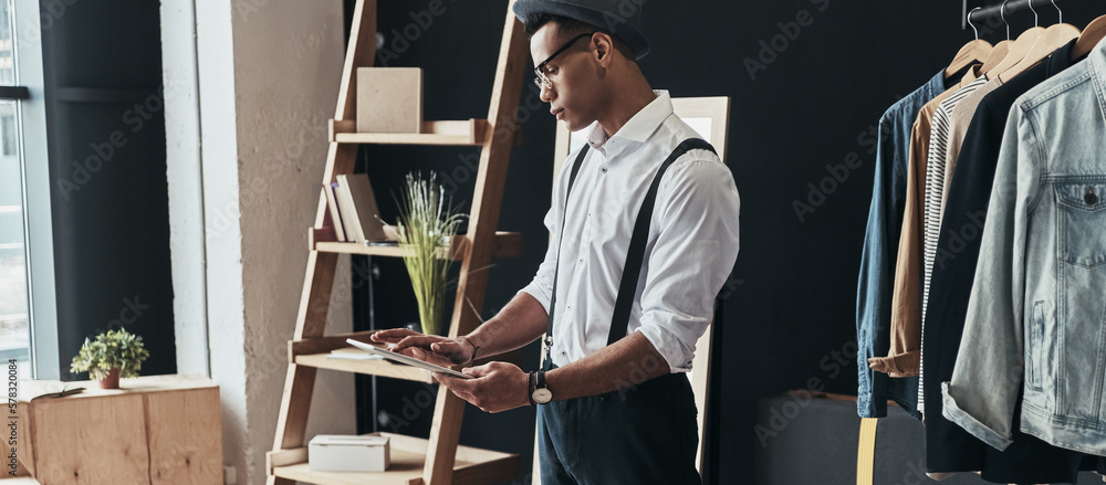 Fashionable young African man using digital tablet while standing in the retail store