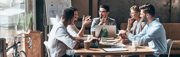 Group of young people discussing business while having meeting in the office