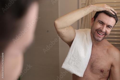 Cute shirtless man looking at his reflection in the bathroom 