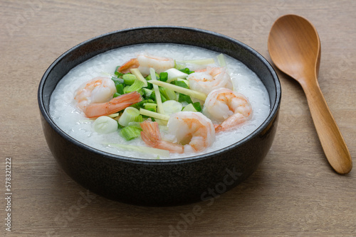 close up of rice porridge with shrimp in a ceramic bowl on wooden table. asian homemade style food concept.
